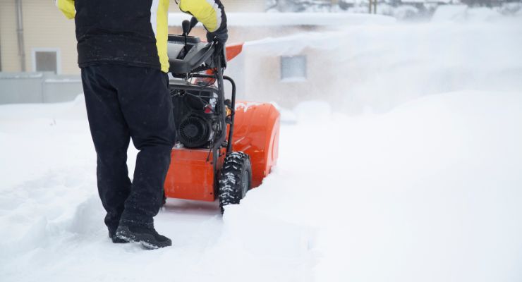 Man pulling the snow blower in snow
